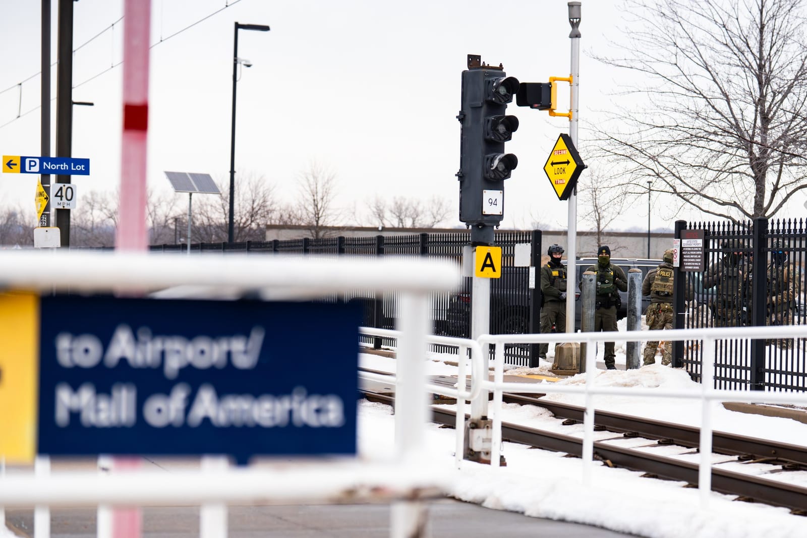 Federal agents outside the Bishop Henry Whipple Federal Building in Minneapolis, Jan 8, 2026, seen from the light-rail station across the way; distant wide view.