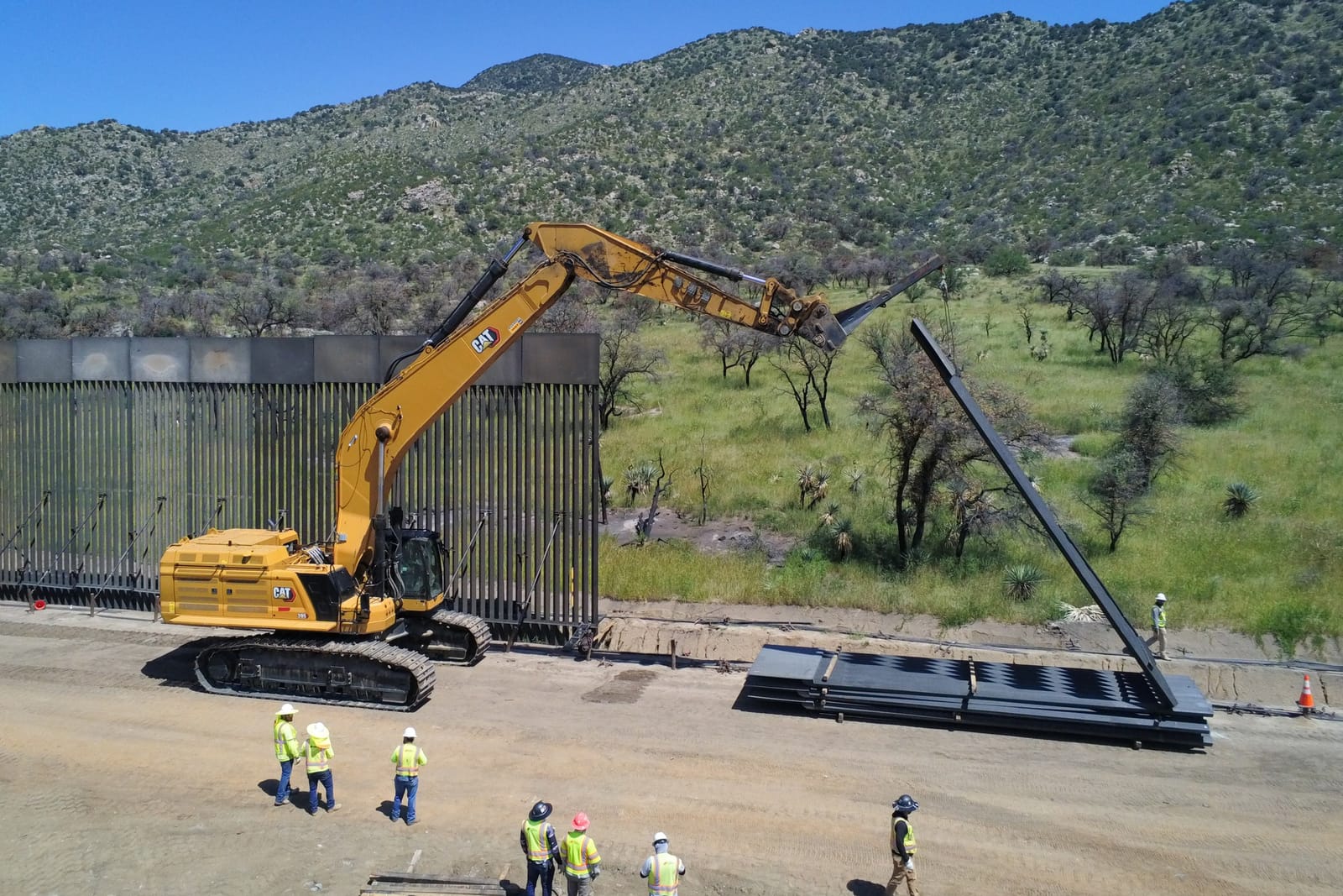 Workers installing prefabricated panels for the new border wall system east of Nogales, Arizona, Aug 27, 2026 (drone view)