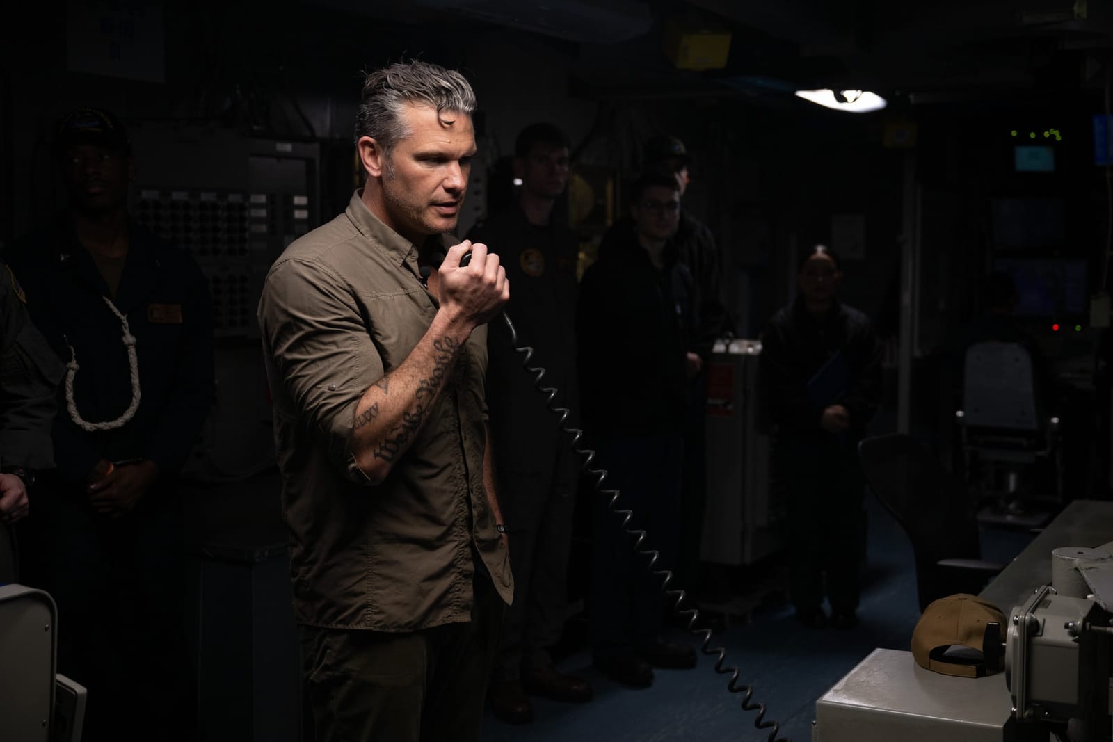 Secretary of War Pete Hegseth speaks into a ship intercom handset aboard the USS Abraham Lincoln.